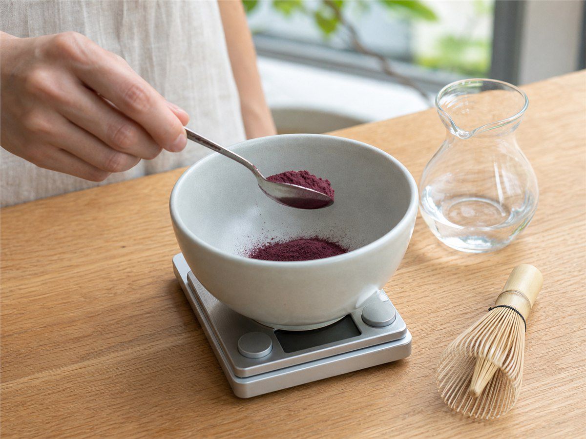 Dosaggio del preparato TAIAO Superfood Acai Latte in una ciotola su bilancia